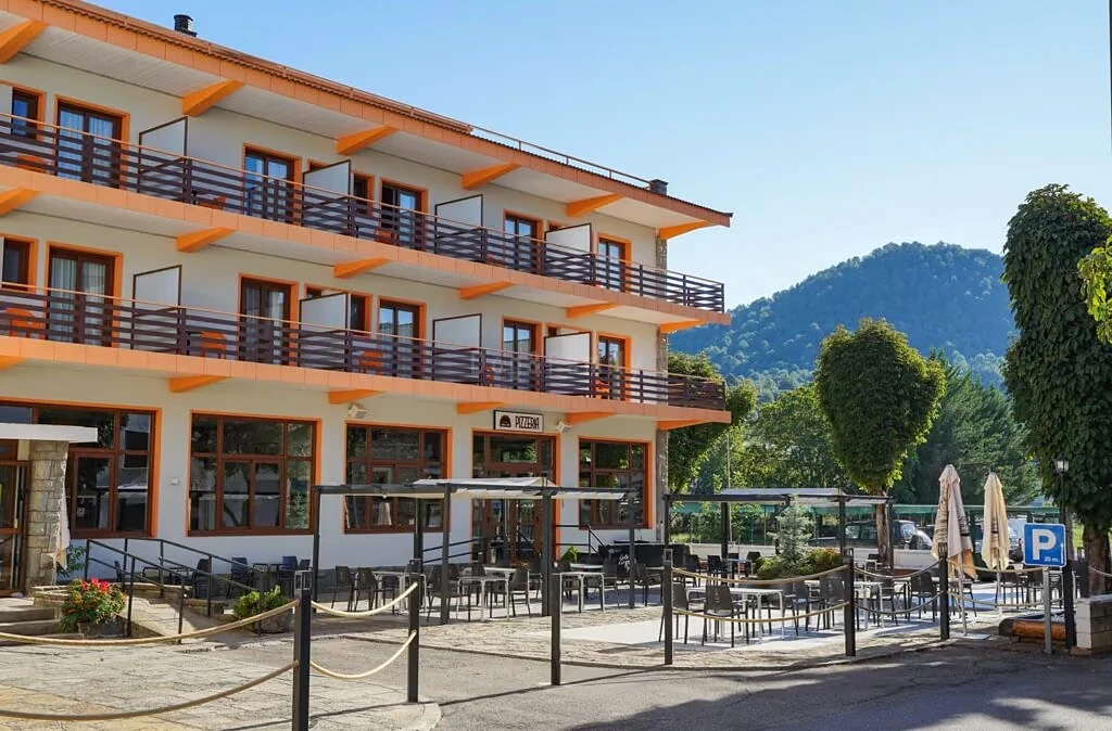 Fachada y terraza exterior de un hotel de montaña rodeado de arbolado